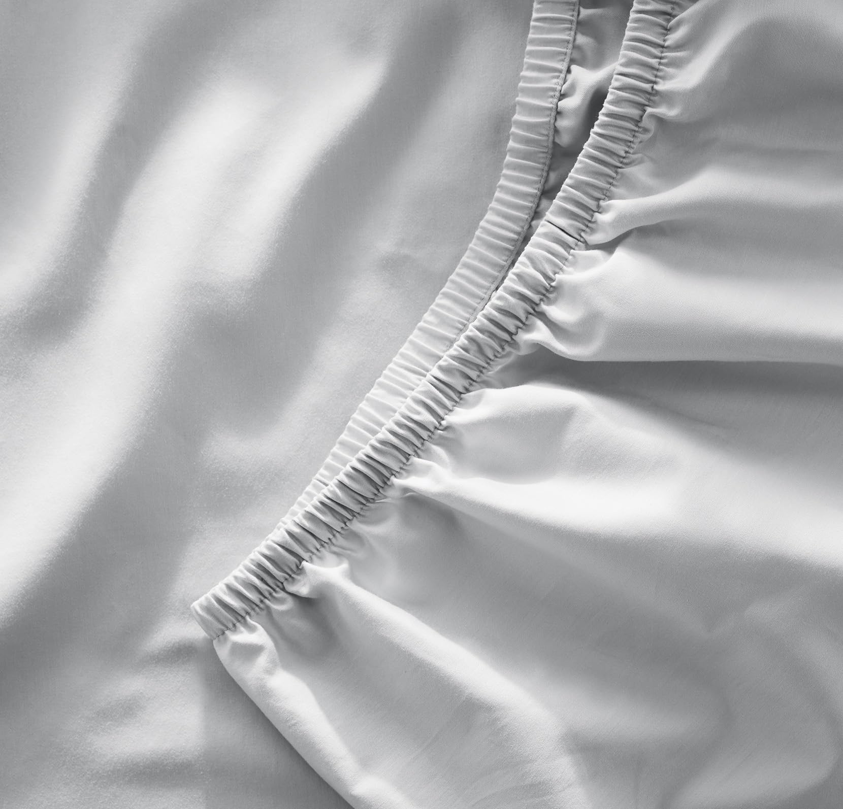 Boll & Branch signature crib sheet sky close-up showing secure elastic for snug fit.