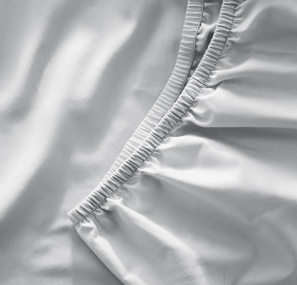 Boll & Branch signature crib sheet sky close-up showing secure elastic for snug fit.