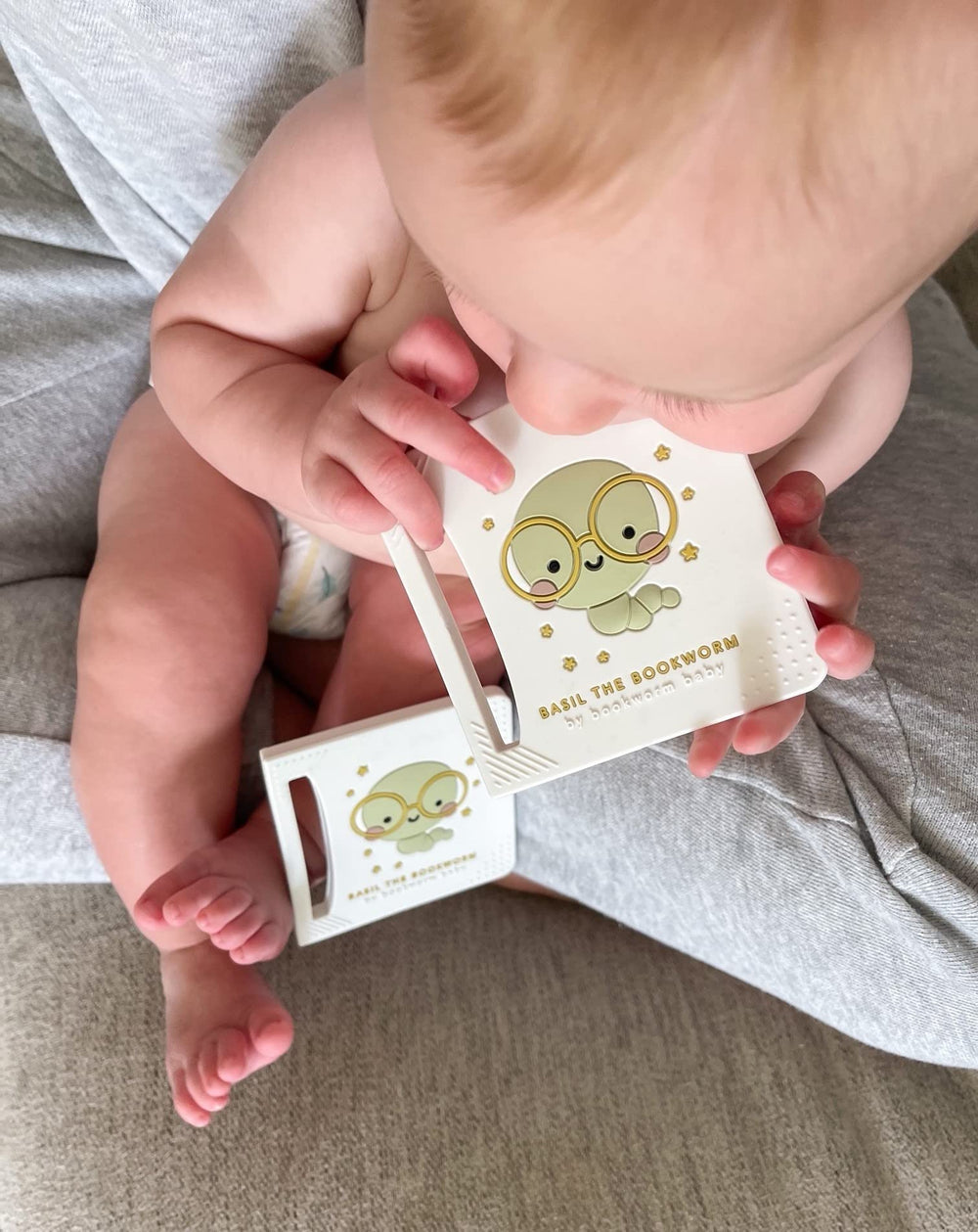 Bookworm Basil teether held in small hands for easy grip and self-soothing