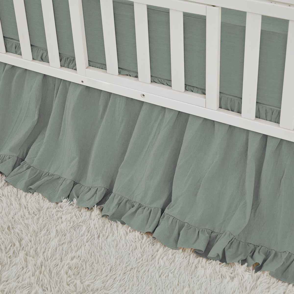 Brandream crib skirt in sage green with ruffles that hide under-crib storage.