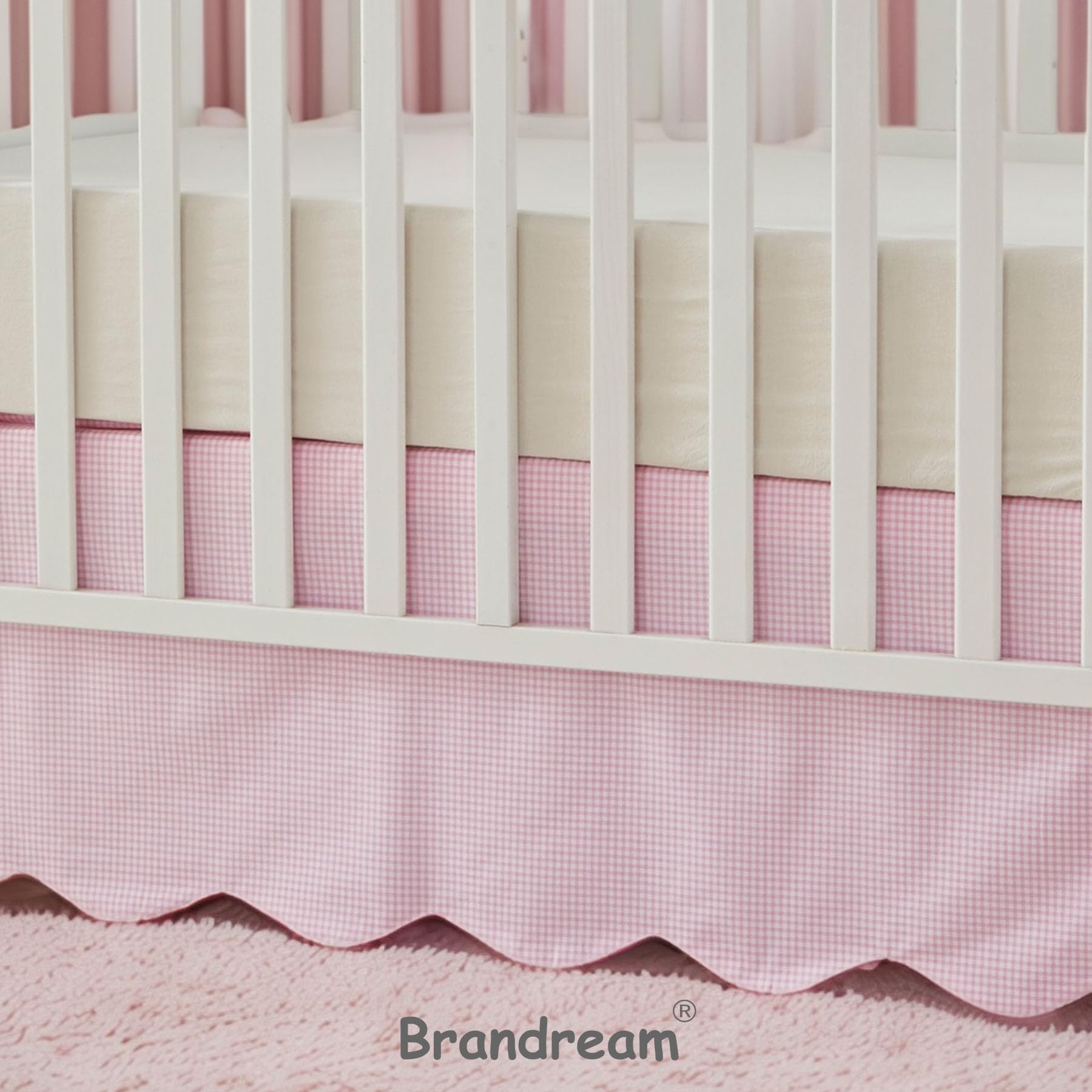 Brandream scallop edge crib skirt on bed demonstrates complete coverage.
