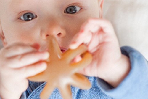 Calmies teether in infant hand demonstrates easy-grip for calming play.