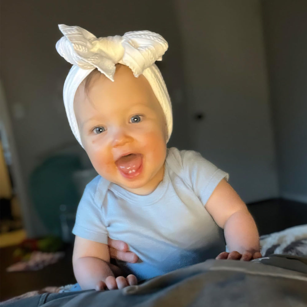 CELLOT nature color 7 baby wears bow headband during playtime.
