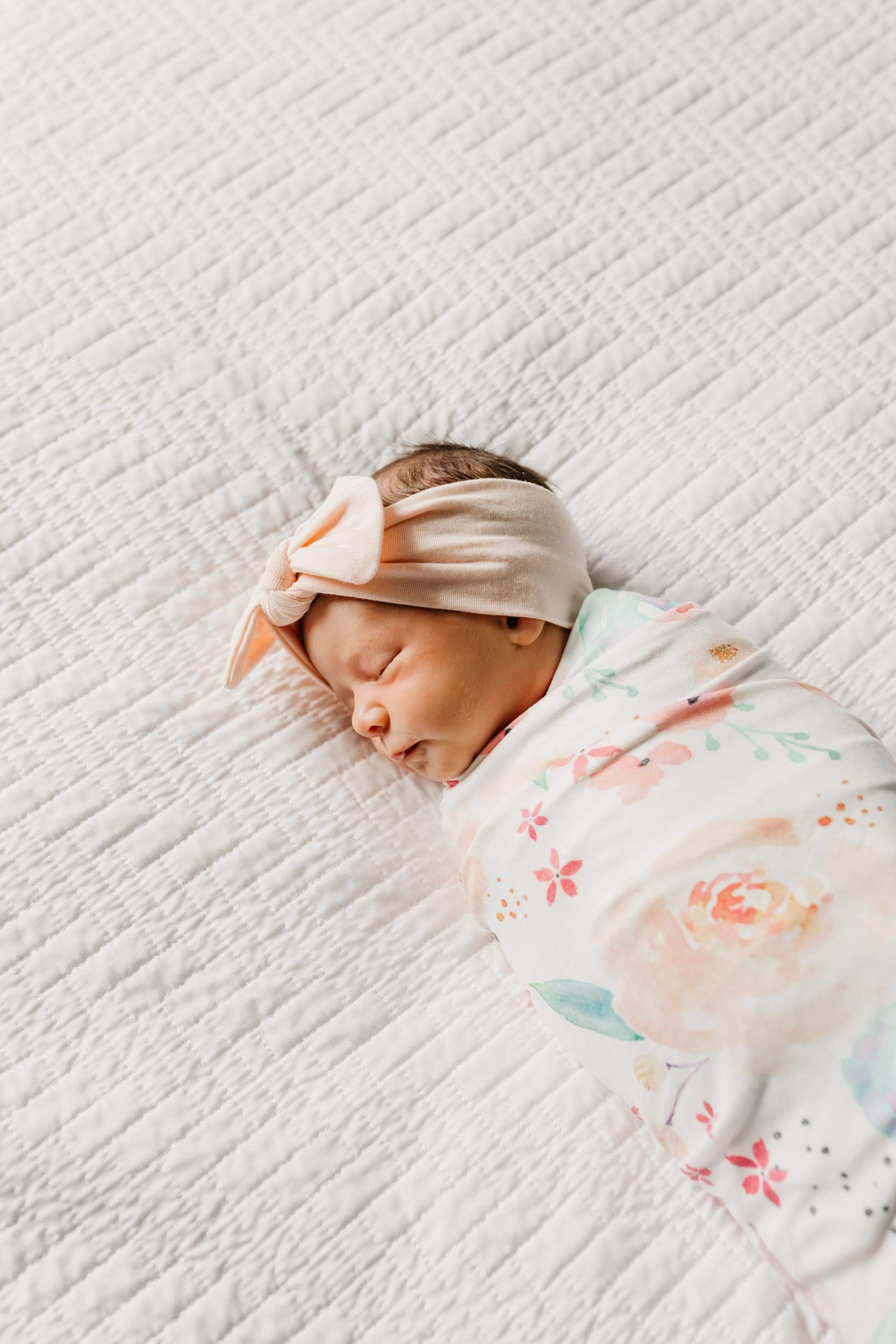 Copper Pearl Floral Bloom swaddle in use with baby's arms out for a relaxed wrap.