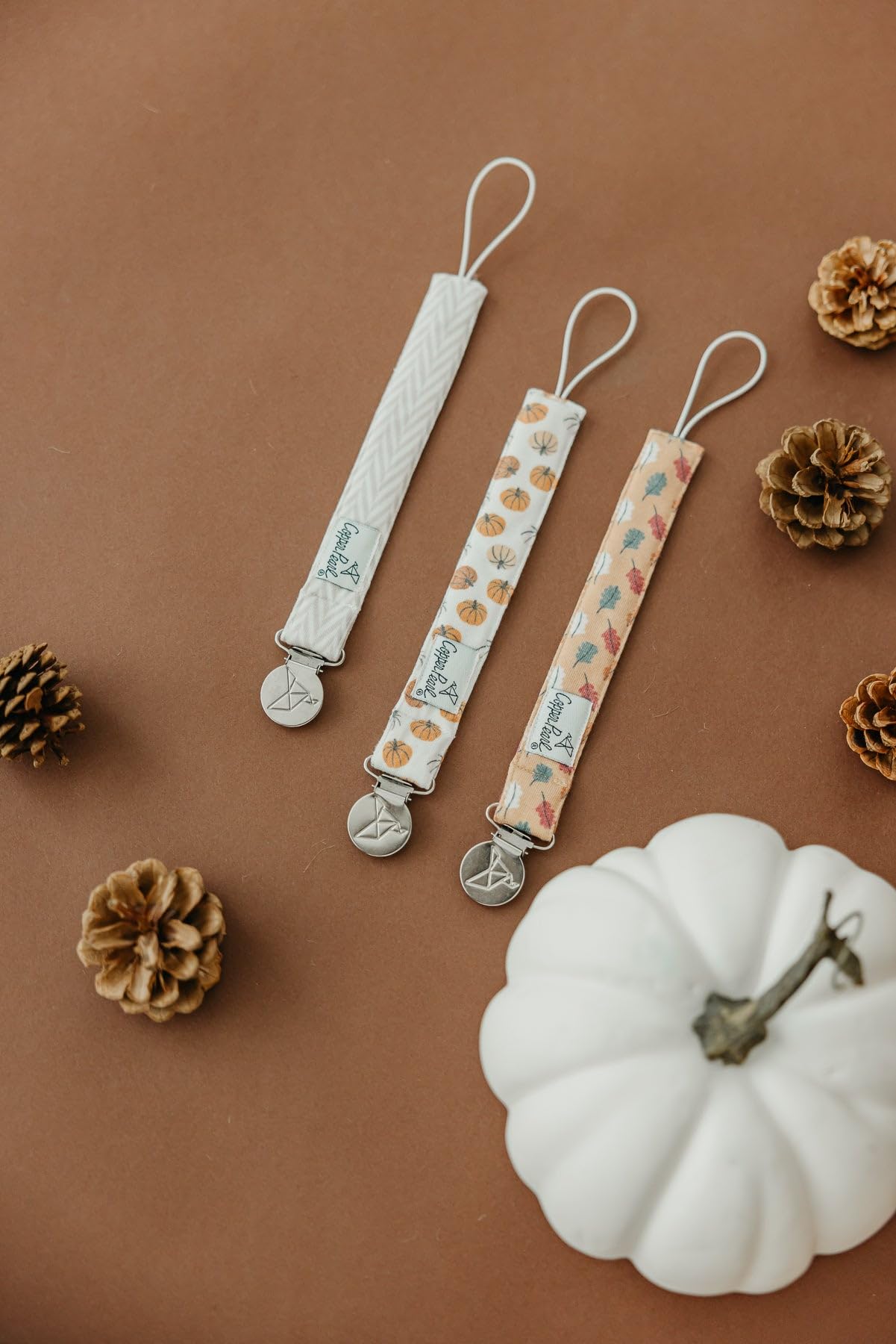 Copper Pearl Karver baby fashion pacifier clip shows coordinated outfit with practical clip