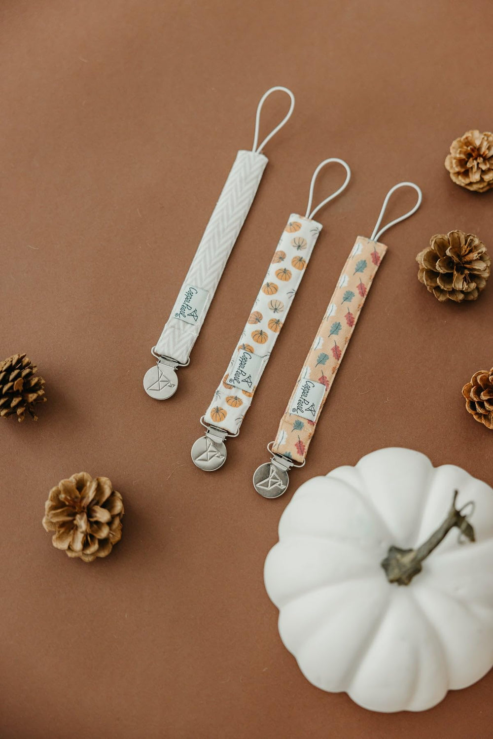 Copper Pearl Karver baby fashion pacifier clip shows coordinated outfit with practical clip