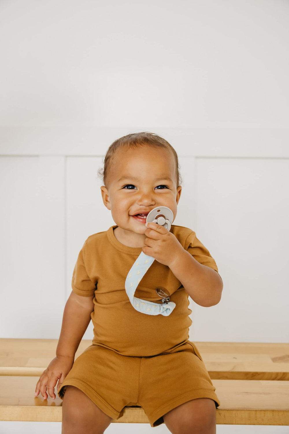 Copper Pearl premium-knit pacifier clips arranged in a trio, gift-ready.