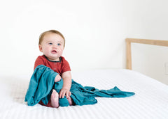 Copper Pearl steel swaddle blanket worn as baby wrap during playtime indoors