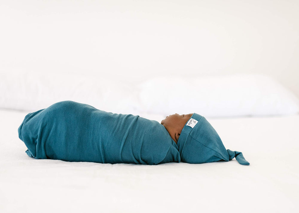 Copper Pearl steel swaddle blanket folded on a nursery crib