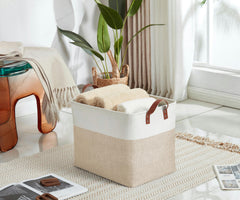 DECOMOMO white fabric basket beside a laundry stack, showcasing versatile clothing storage.