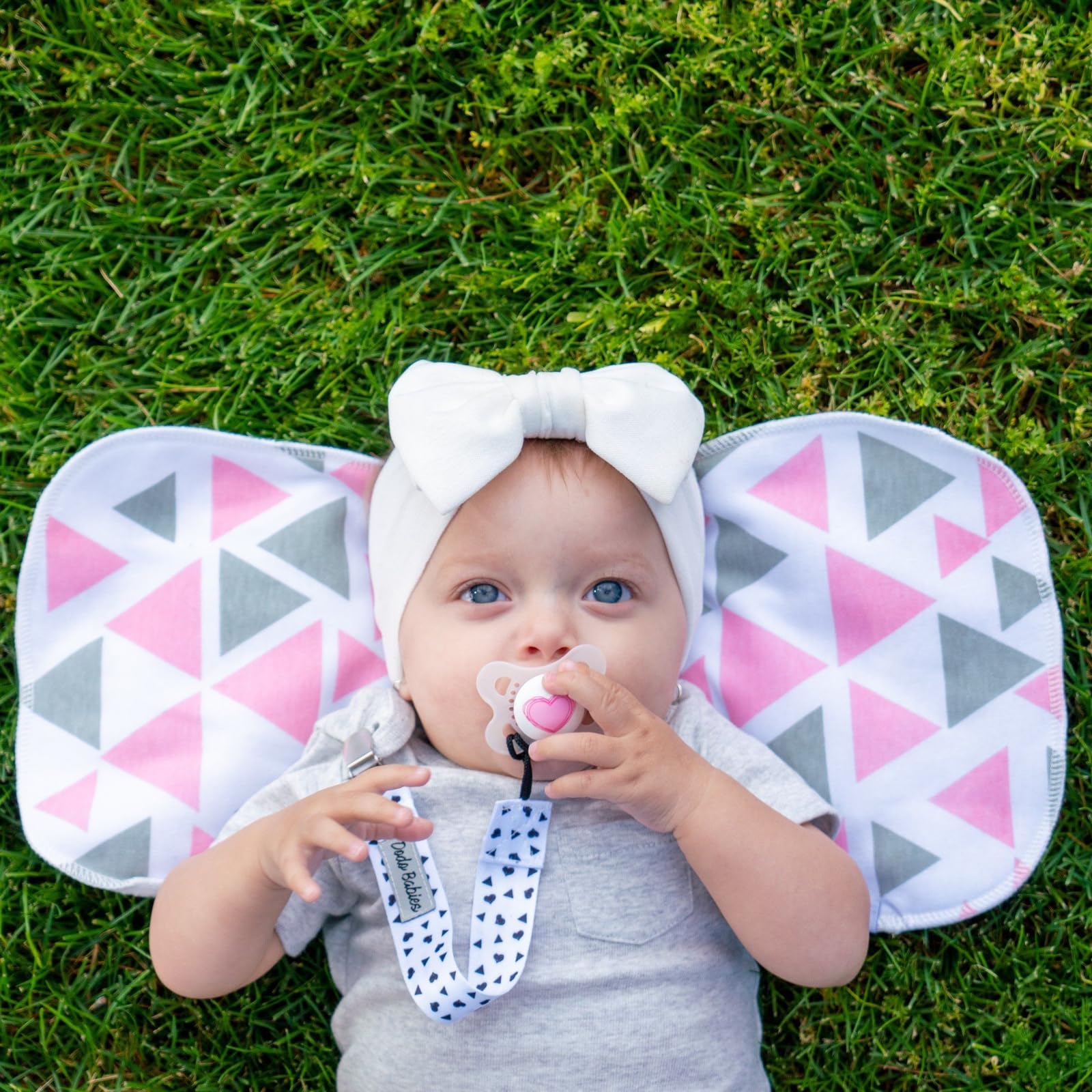 Dodo Babies burp cloths in use on a baby shoulder catching spit-up and drool.