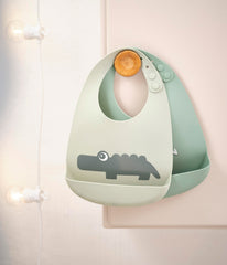 Done by Deer Croco Green silicone bib pocket close-up catching dropped food.