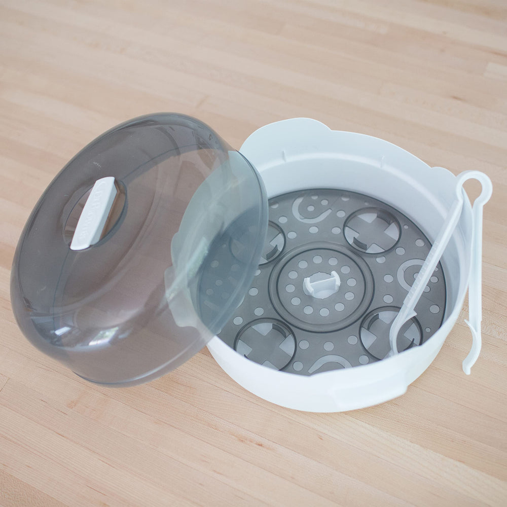 Dr. Brown's HappyPaci pacifiers beside sterilizer illustrate a complete feeding hygiene routine.