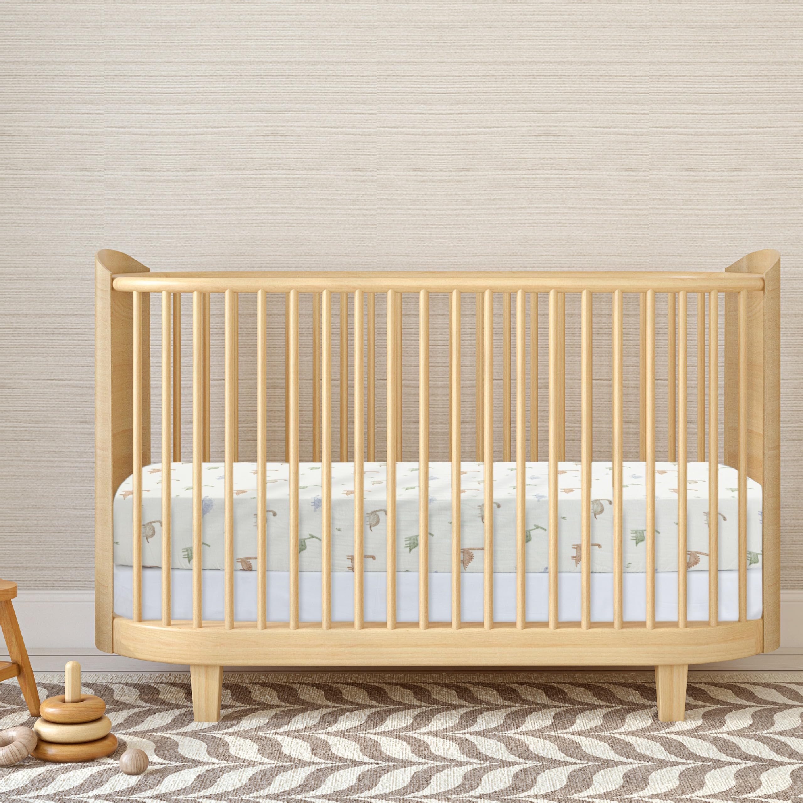 Dreamology nursery setup shows Dino-design crib sheet for a calm space.