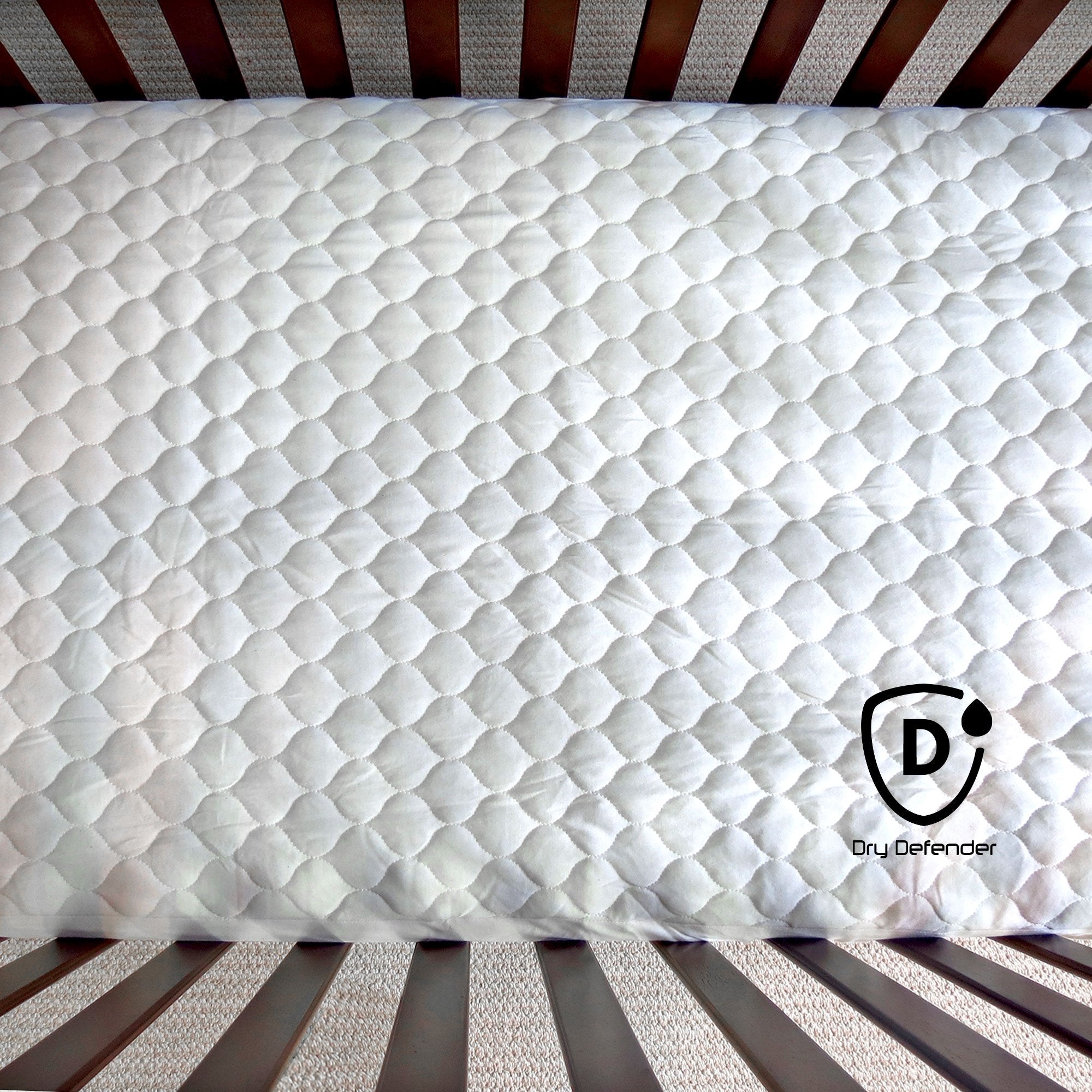 Dry Defender unbleached fabric crib pad in nursery setting