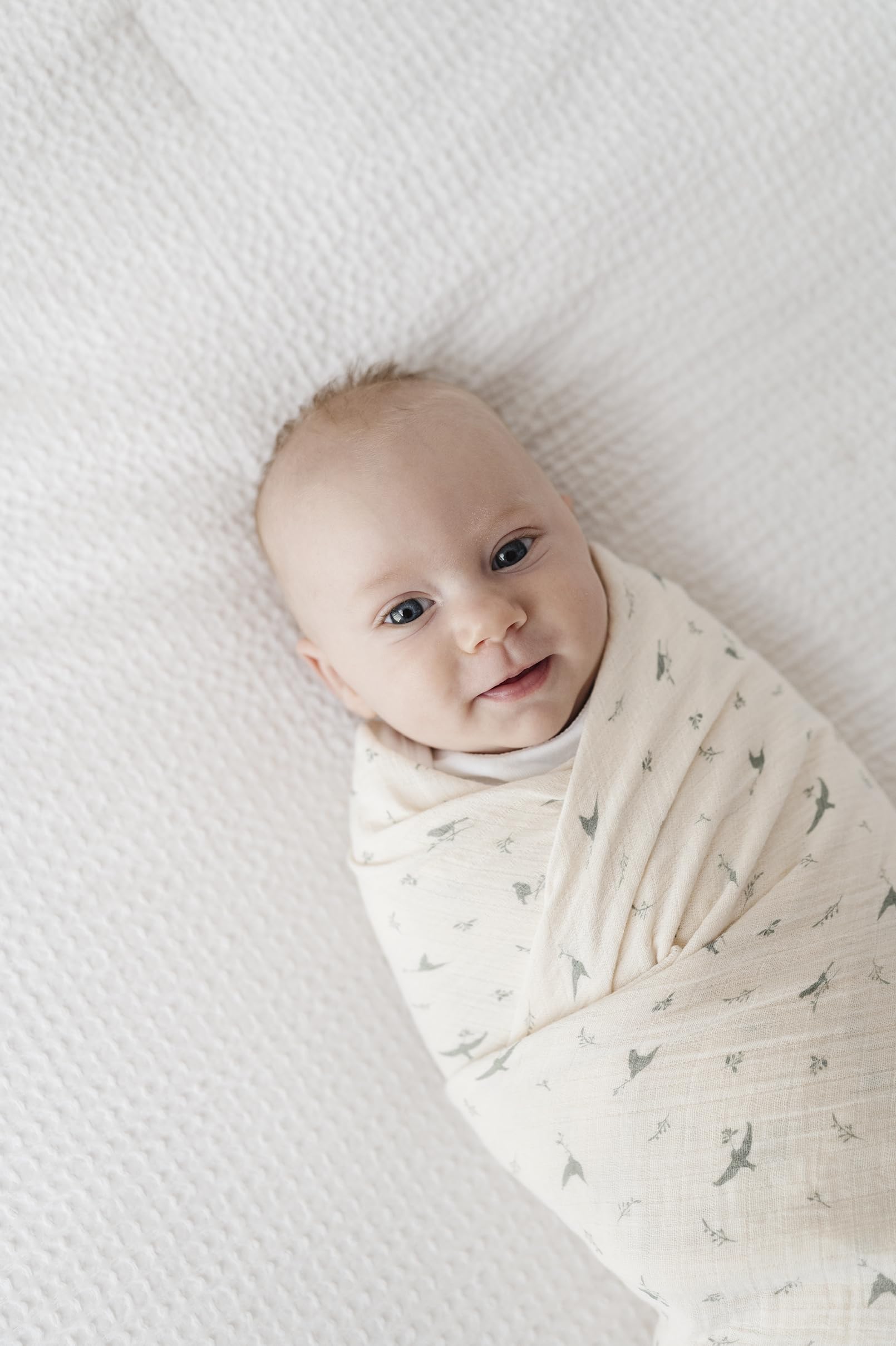 Ely's & Co sage bird swaddle in baby arm shows skin-friendly fabric for cozy snuggles.