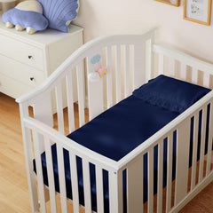 Entisn satin crib sheets on-bed view shows navy color complementing nursery decor.