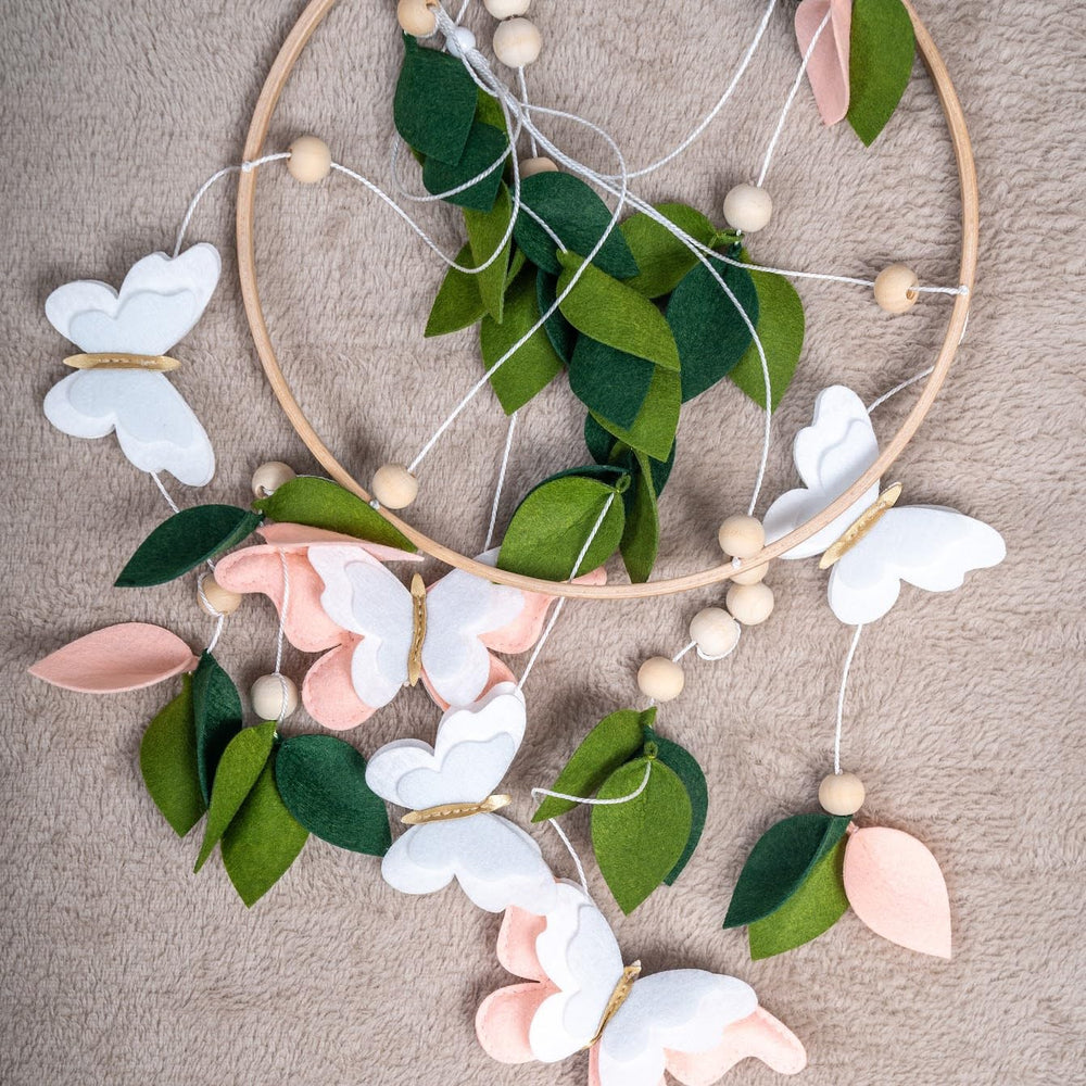 Flora & Ivy butterfly mobile hanging setup demonstrates universal compatibility with crib arms.