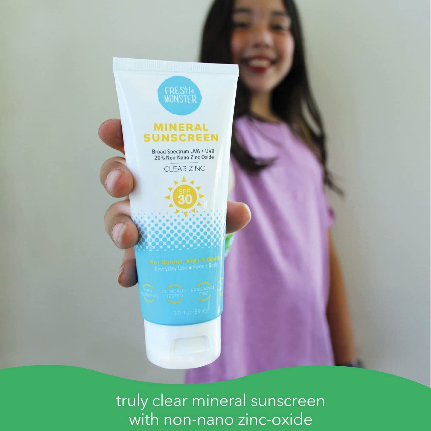 Fresh Monster Daily Kids Sunscreen bottle applied on child's face during sunny outdoor activity.
