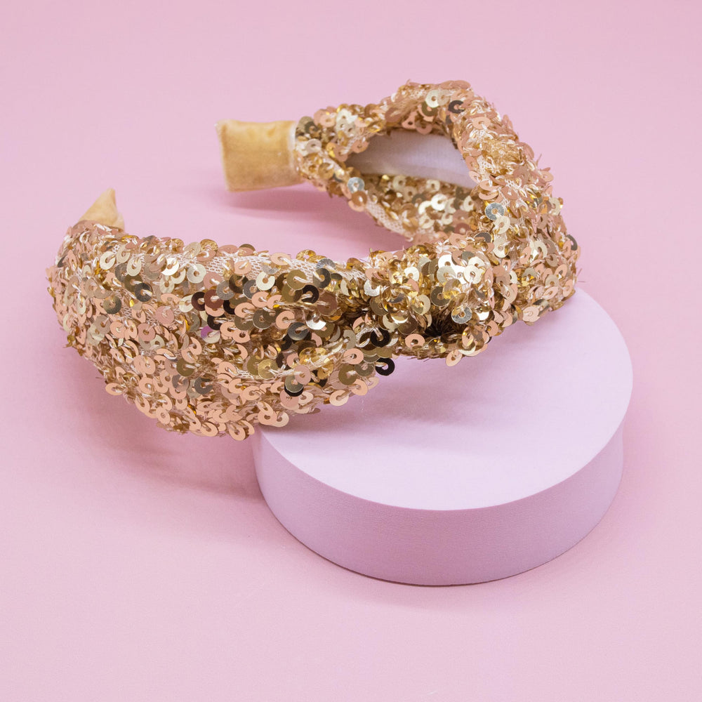 FROG SAC knot-detail gold headband shows the playful, bold knot design.