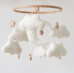 GOUKURLSMA cloud mobile in neutral cream tones harmonizes with boho nurseries and softens lighting.