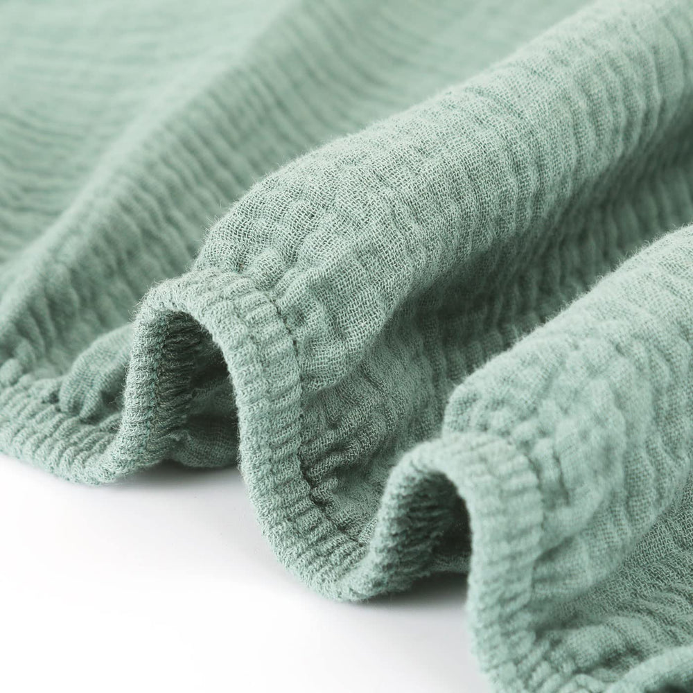 GRSSDER Roman Green crib sheet on a baby sleeping scene in a calm nursery