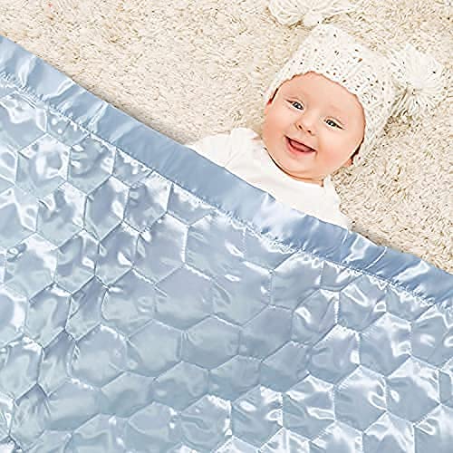 Heavens Cuddles quilted satin baby blanket light blue in hands suggests comforting bedtime routine.