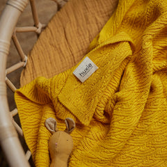 Huxie blanket laid in crib setup for cozy nighttime warmth