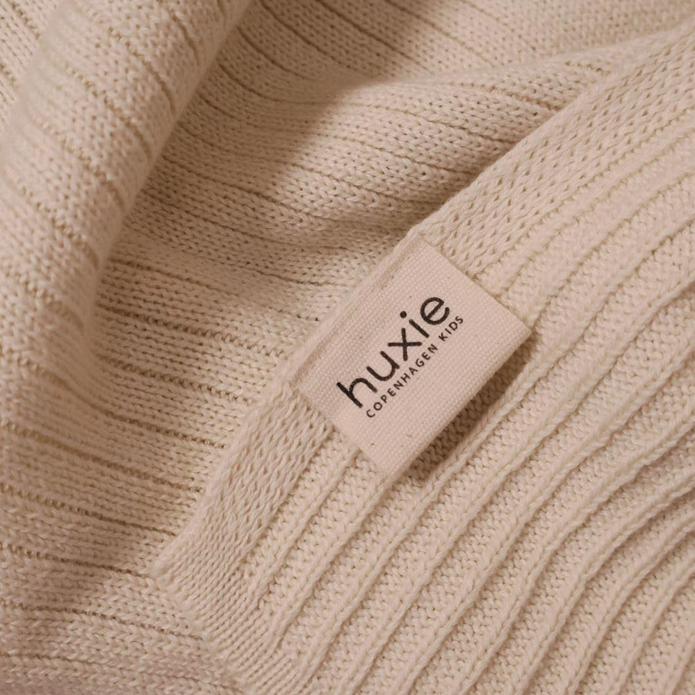 Huxie crib use shot demonstrates blanket as a gentle receiving layer.