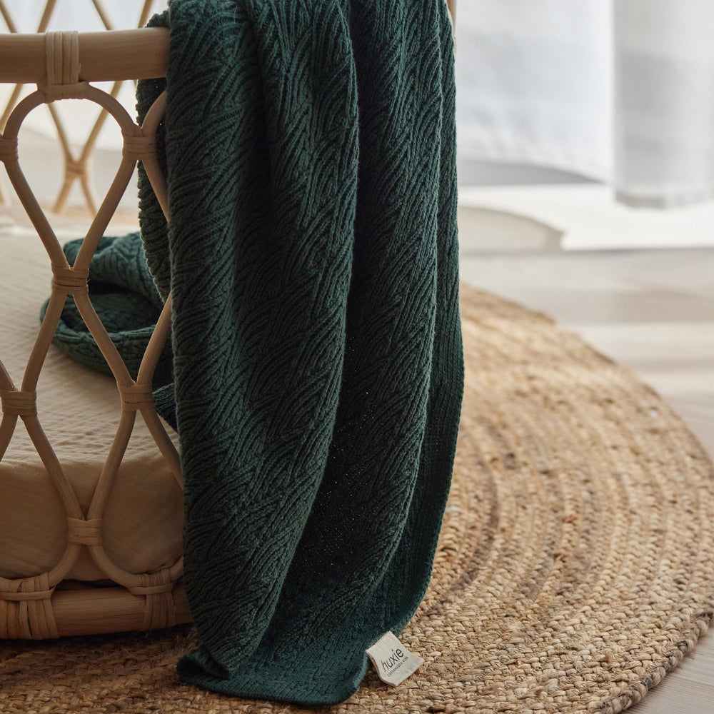 Huxie Knitted Baby Blanket beside crib highlights cozy nursery style