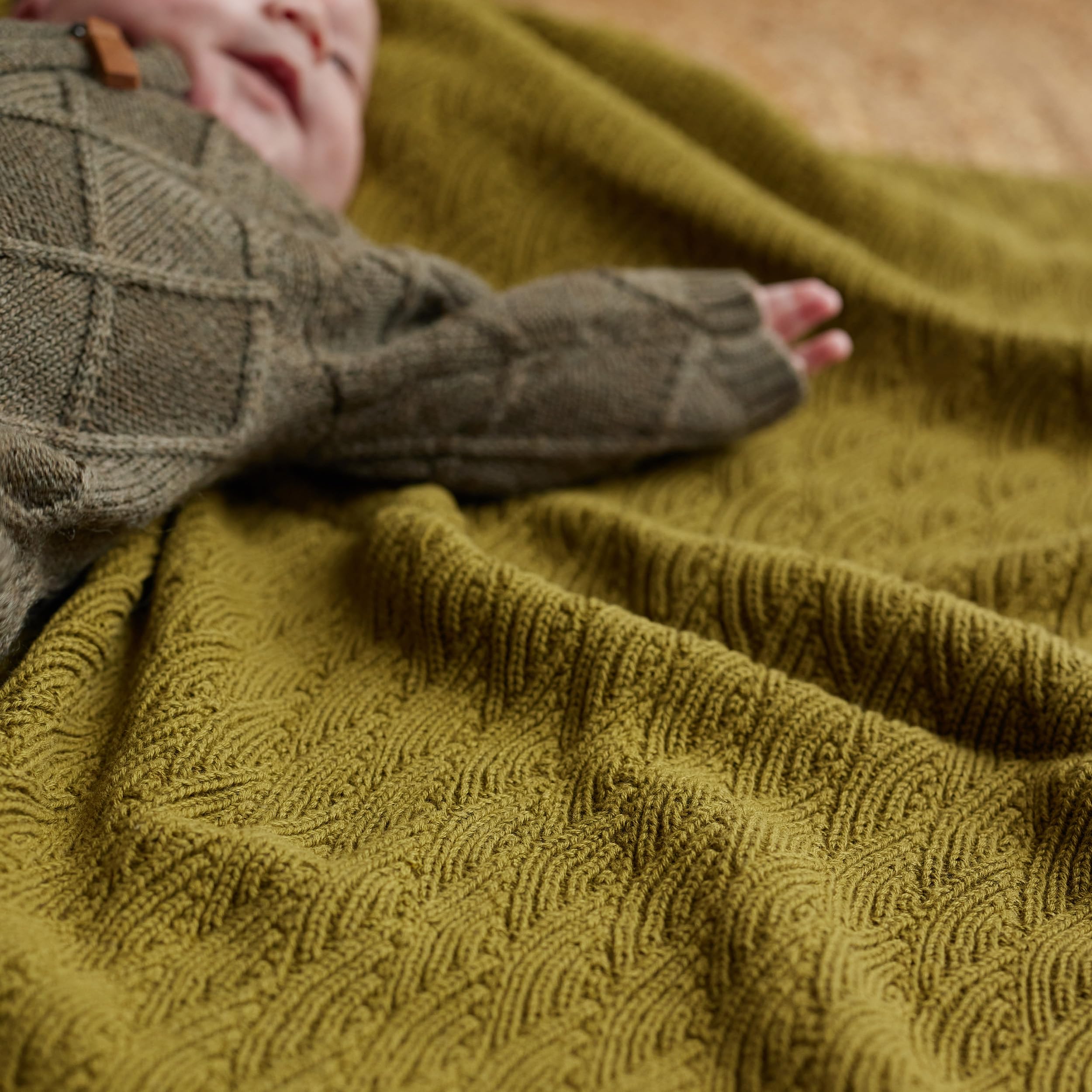 Huxie knitted baby blanket moss green gender-neutral design on neutral backdrop