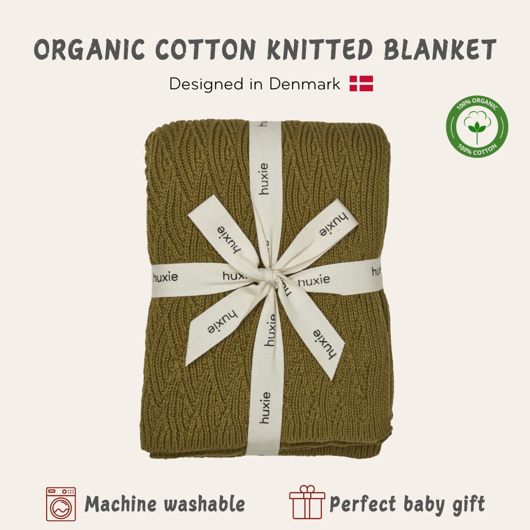 Huxie knitted baby blanket moss green in crib setup emphasizing warmth and breathability