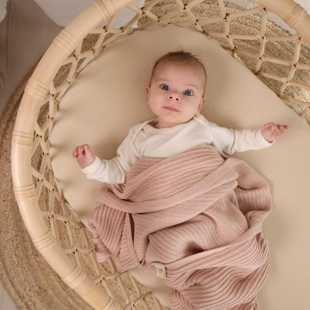 Huxie knitted blanket in crib highlighting versatile use for newborns.
