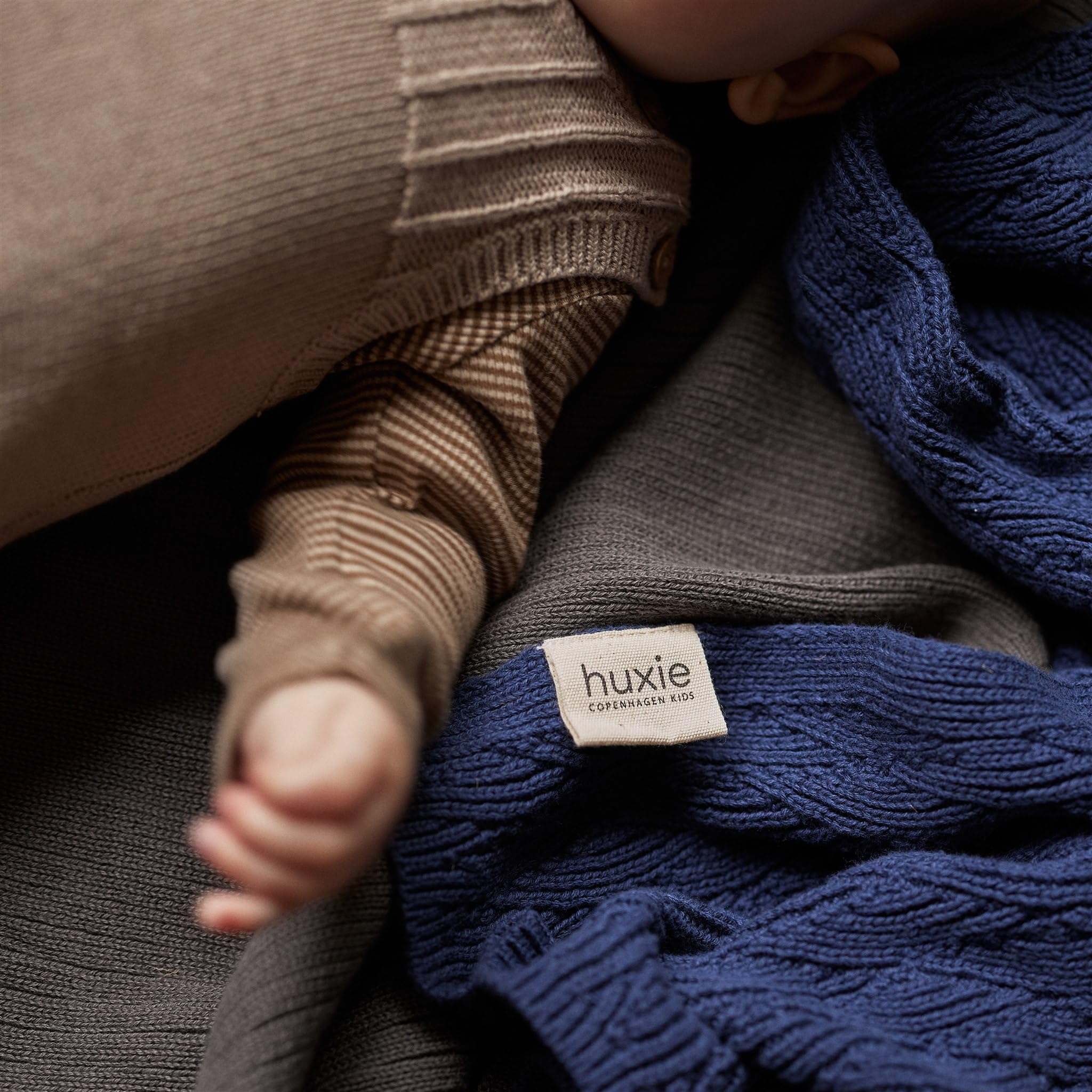 Huxie Knitted Baby Blanket stone grey color swatch conveys timeless neutral style.