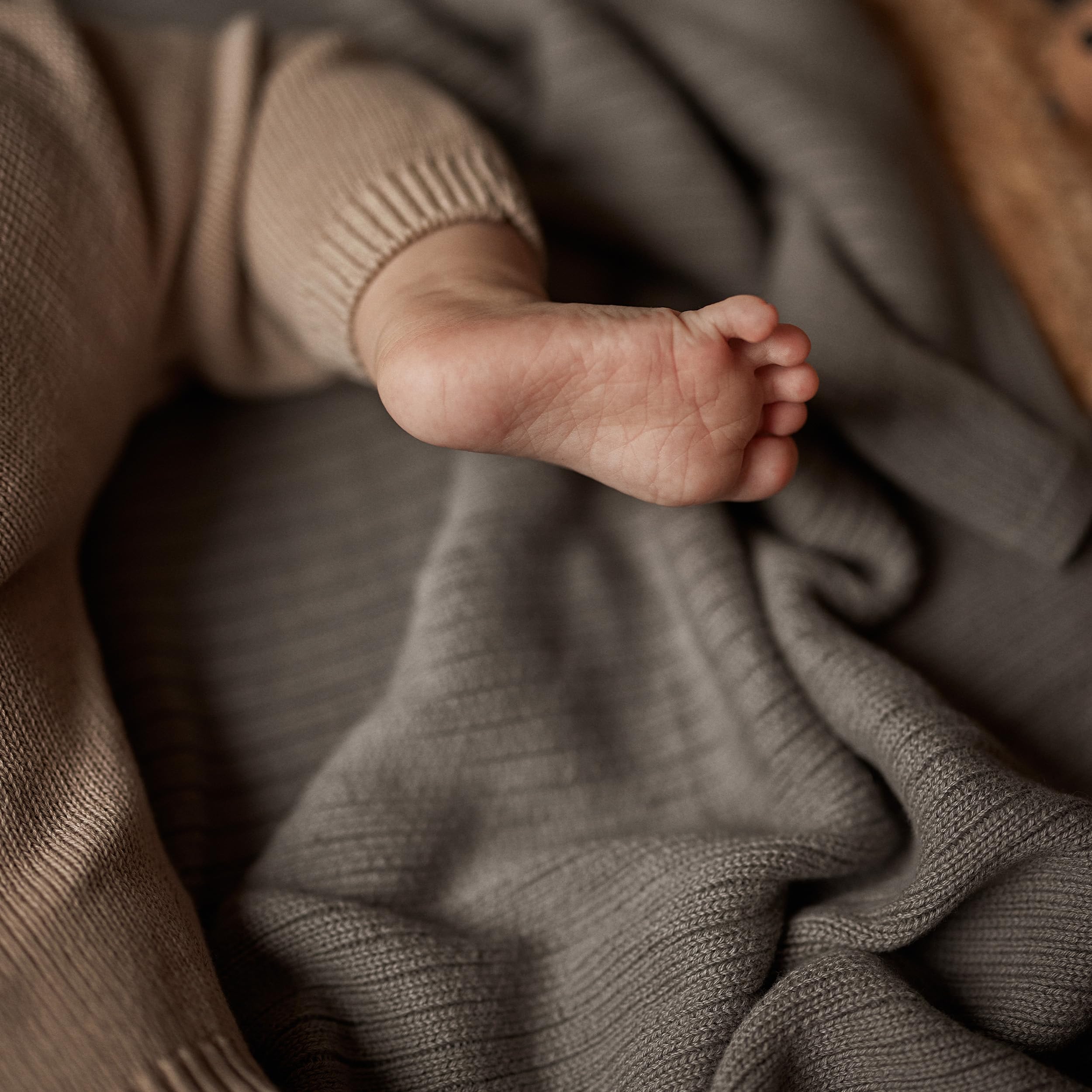 Huxie Knitted Baby Blanket in stroller scene demonstrates portable warmth on the go.
