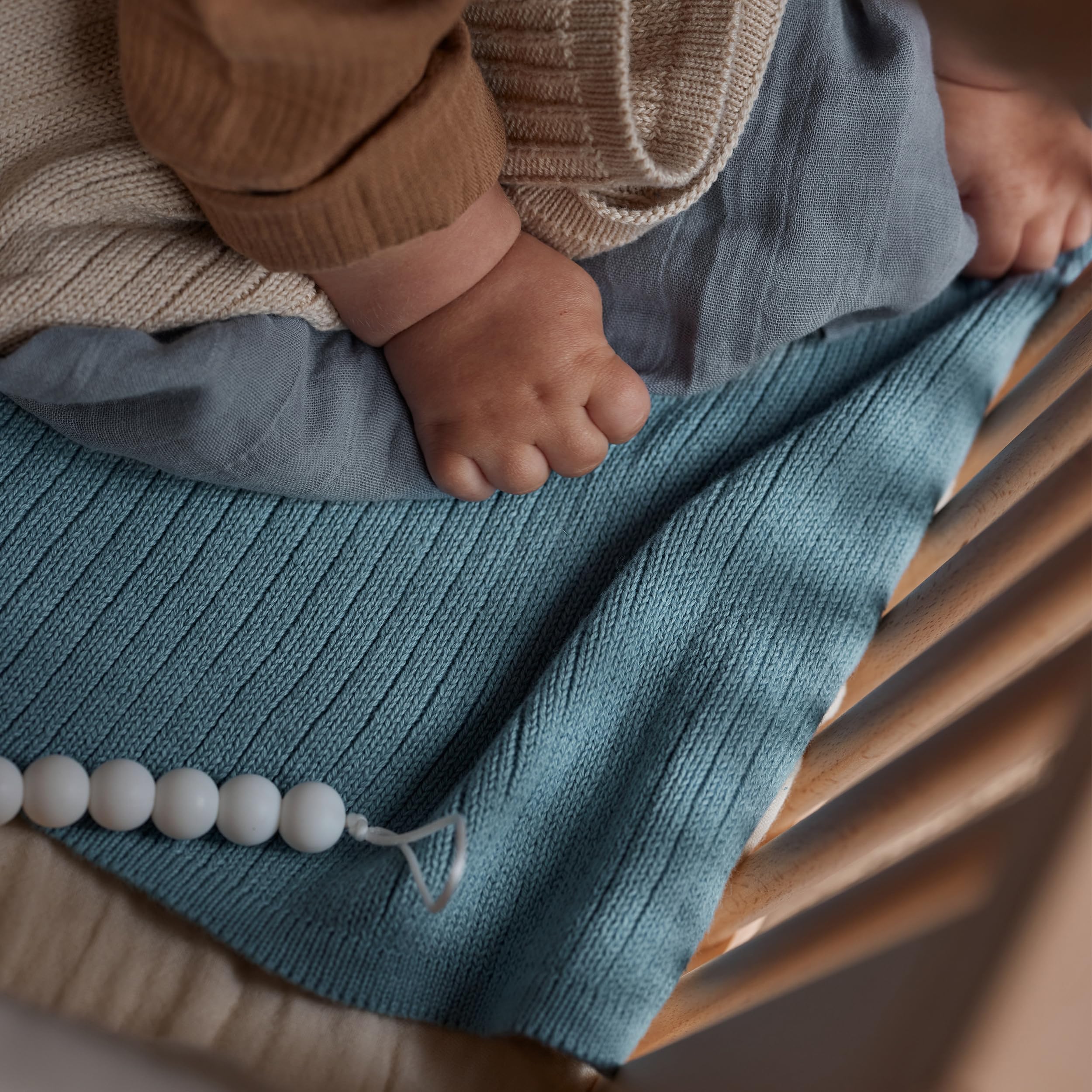 Huxie knitted baby blanket in stroller shows versatile travel warmth.
