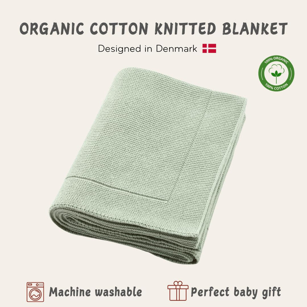 Huxie knitted organic baby blanket in crib setting demonstrates all-season warmth and breathability.