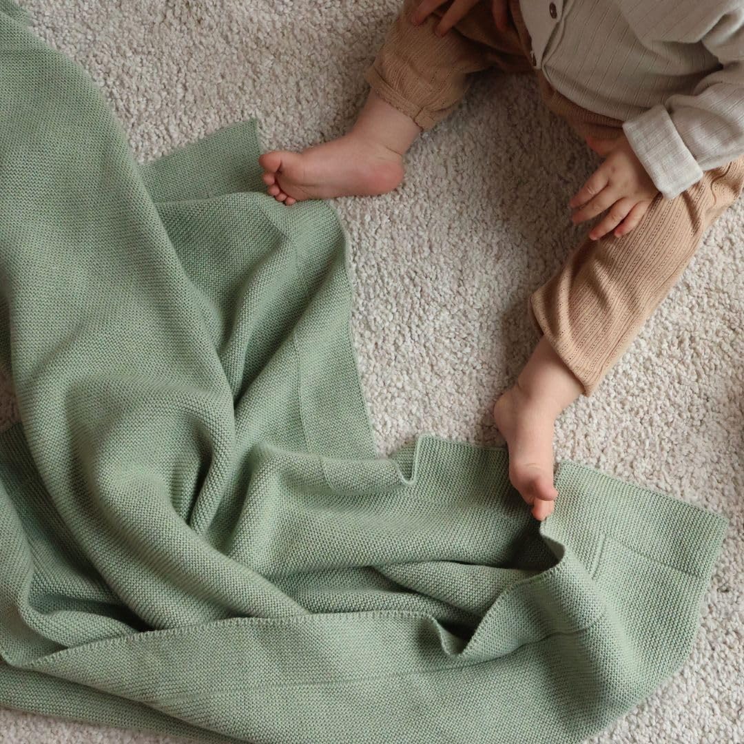 Huxie knitted organic baby blanket care guide shows gentle washing and low tumble dry.