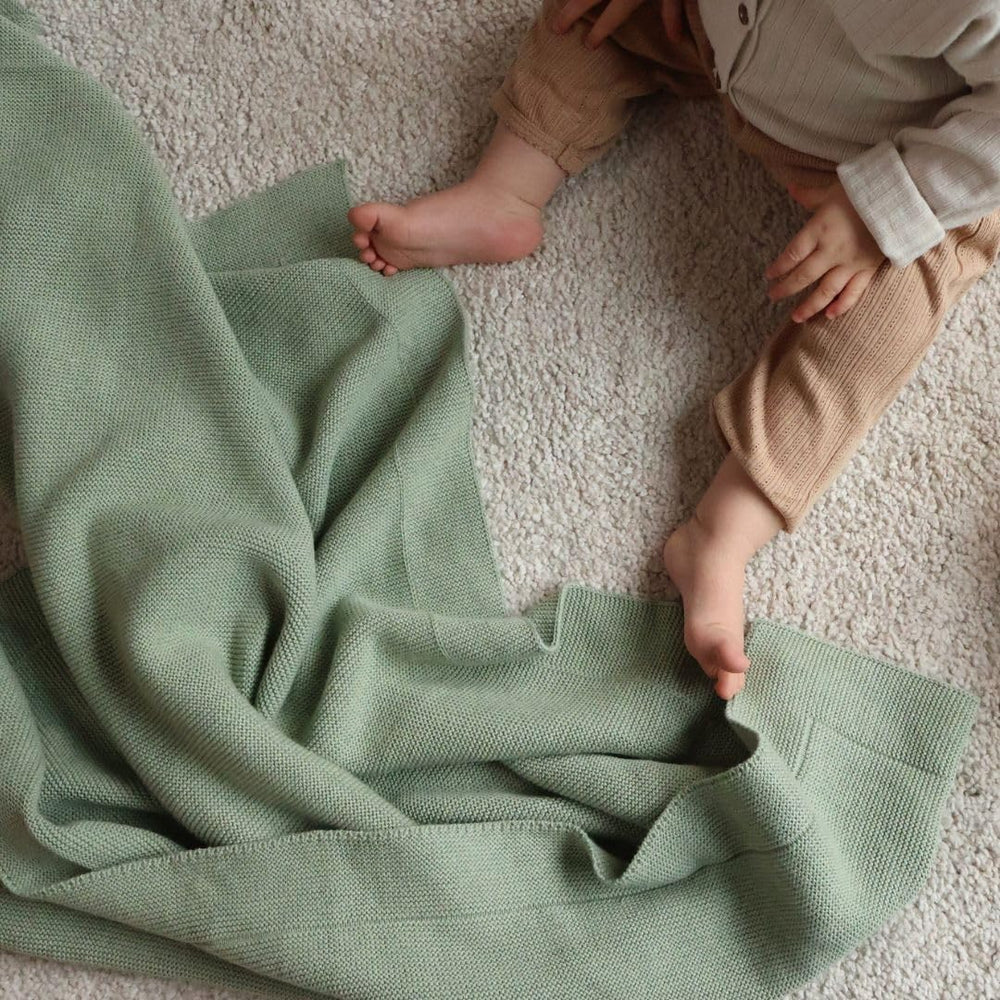 Huxie knitted organic baby blanket care guide shows gentle washing and low tumble dry.