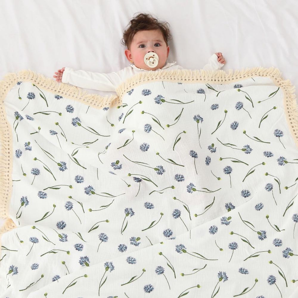 Insular cotton muslin baby blanket blue dandelion tassels closeup highlights four-sided boho fringe for cozy decor.