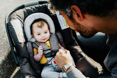 JJ Cole seat belt cover attachment demonstrates easy hook-and-loop wrap around car straps.