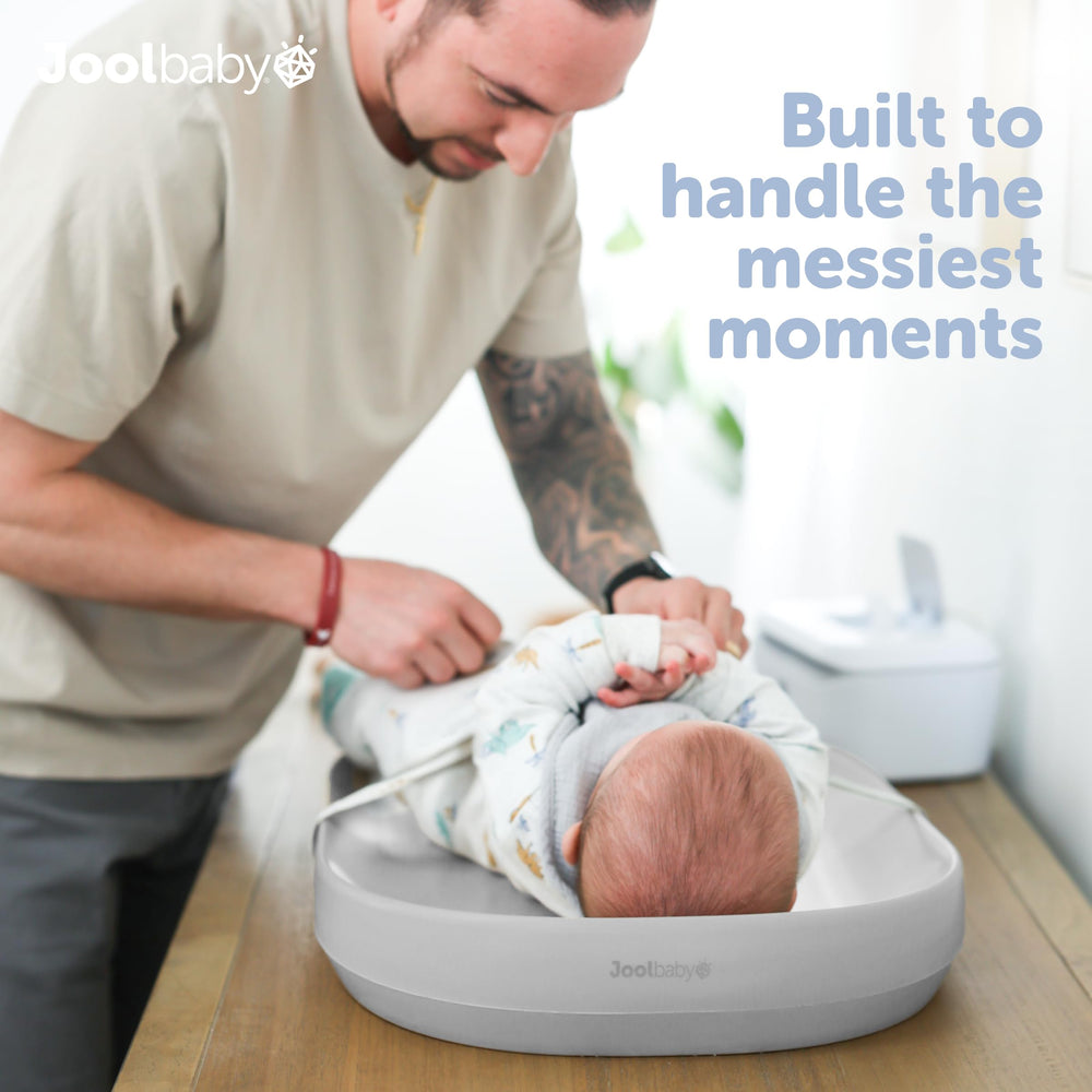 Jool Baby waterproof changing pad gray side-strap shows secure positioning during diaper changes.