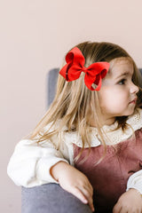 JUCCPUL 6-inch red bow attached to a sturdy clip for secure ponytails