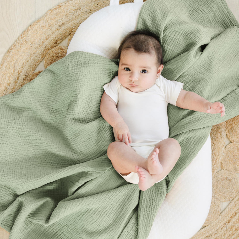 Konssy muslin swaddle blankets flatlay in woodland-sage with soothing unisex tones and texture.