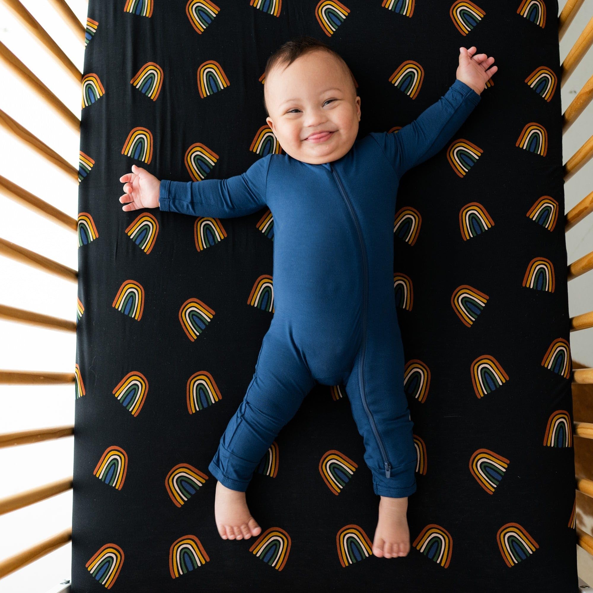 Kyte Baby crib sheet Rust Rainbow on Midnight folded for compact storage.