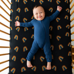 Kyte Baby crib sheet Rust Rainbow on Midnight folded for compact storage.