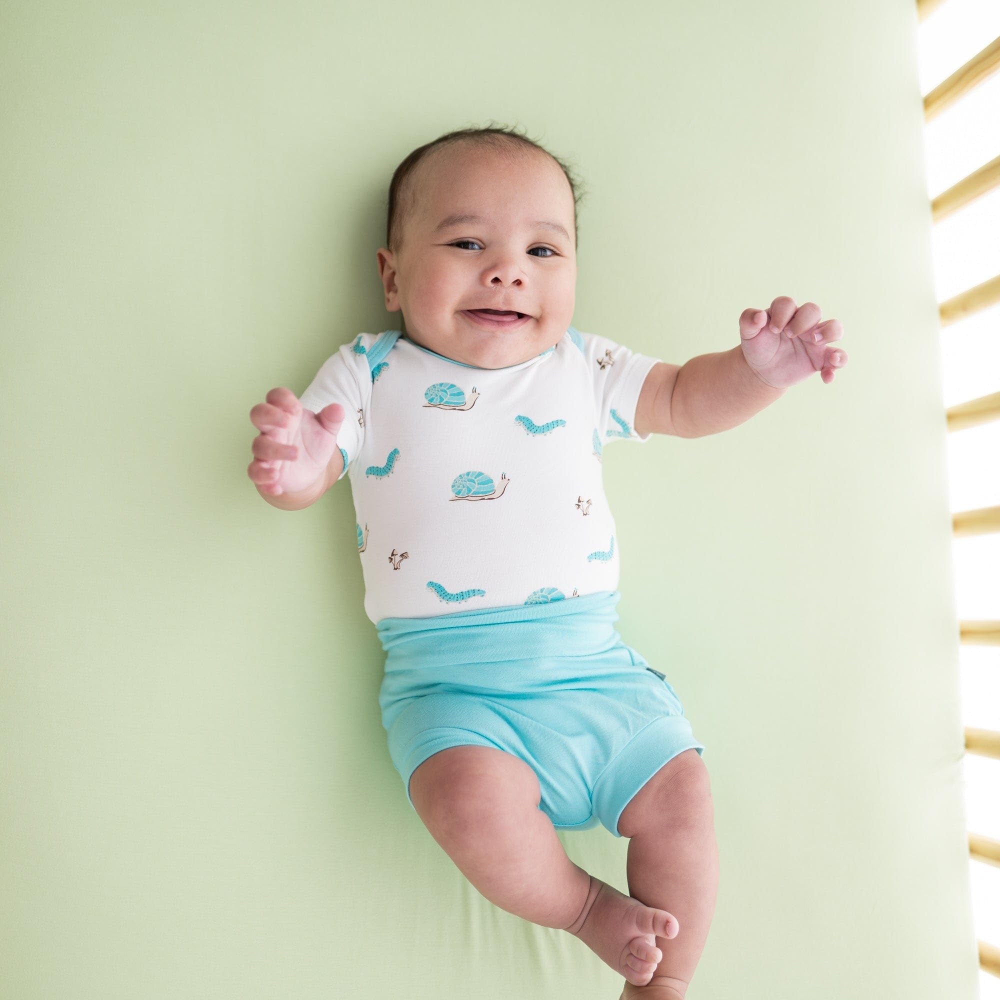 Kyte Baby pistachio crib sheet stretch-fit on mattress illustrating secure tuck