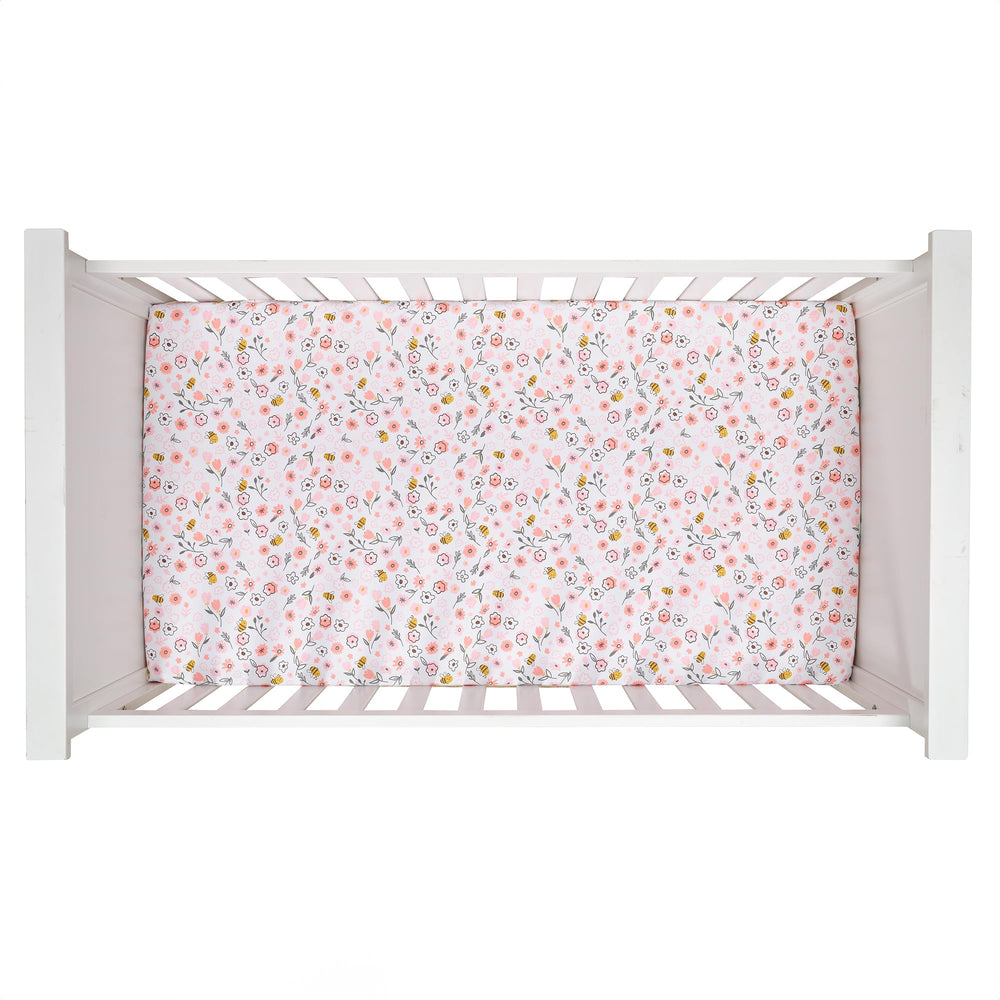 Lambs and Ivy Little Garden Sheet close-up, cotton fabric shows pastel pink flowers and delicate texture.