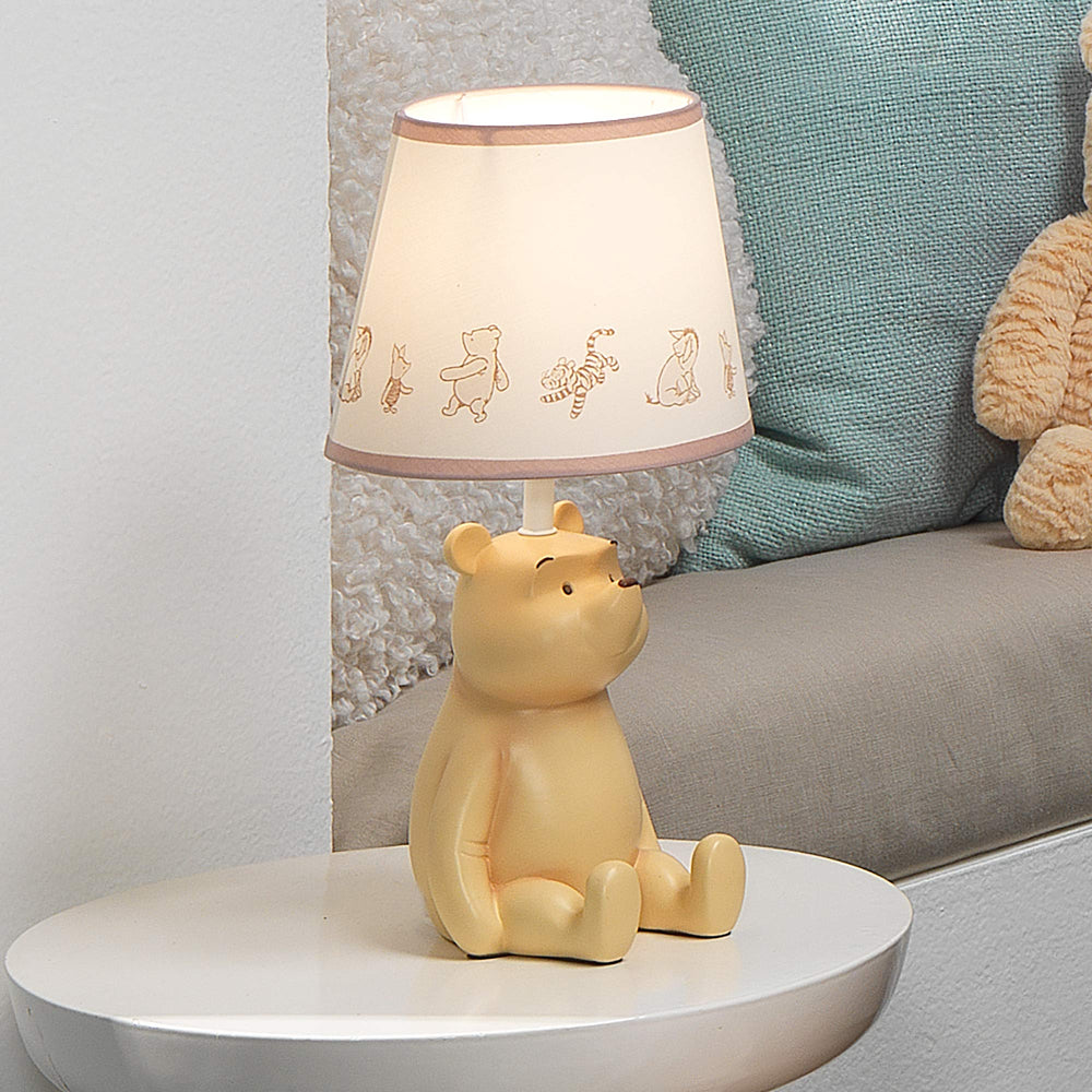 Lambs & Ivy Storytime lamp on a nursery table provides warm bedtime glow.