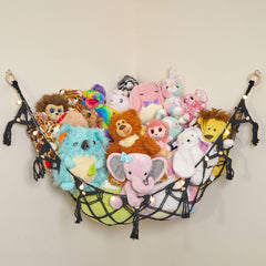 Lilly's Love macrame hammock stores plush toys with warm string lights for cozy playroom storage.